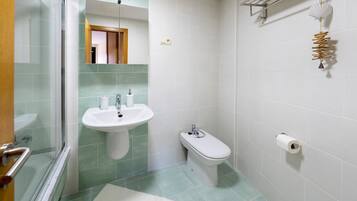 Une salle de bain avec une douche à parois de verre, un lavabo, un bidet et des toilettes.