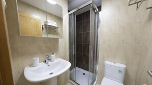 Et badeværelse med vask, toilet og brusekabine med glasvægge.
