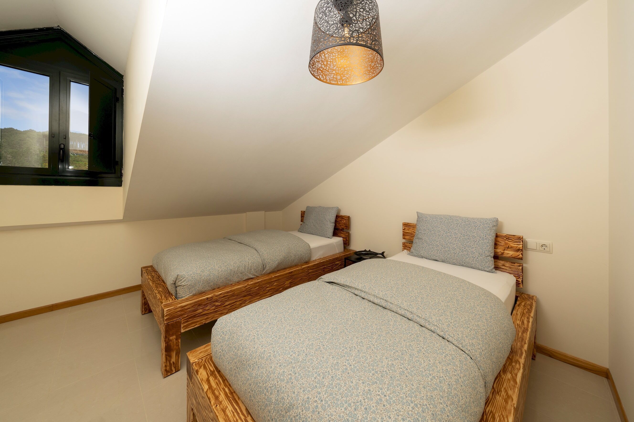 Un dormitorio con dos camas de madera, una ventana y una lámpara colgante.