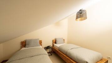 A bedroom with two wooden bunk beds, a small bedside table, and a wall-mounted light fixture.
