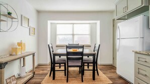 A modern kitchen with a dining table, chairs, a refrigerator, and a window with blinds. - Sunshine Terrace 2BR, perfect for business travel! (Amarillo)