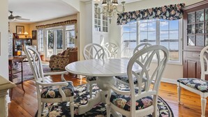 A dining area with a round table and white chairs, a chandelier, and a view of the outdoors. - Short drive to Downtown Cambridge | Private Dock | Guest House | Pool | Hot Tub (Cambridge)