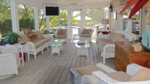 A covered outdoor seating area with white wicker furniture, a ceiling fan, and a TV mounted on the wall. - Short drive to Downtown Cambridge | Private Dock | Guest House | Pool | Hot Tub (Cambridge)
