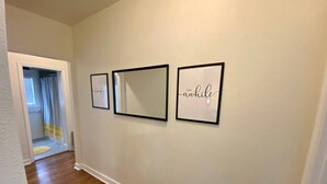 A hallway with wooden flooring and three framed pictures on the wall. - Urban Hideaway - Cozy & Remodeled 2 BR! (Amarillo)