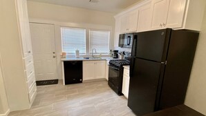 A kitchen with white cabinets, a black refrigerator, a stove, and a dishwasher. - Urban Hideaway - Cozy & Remodeled 2 BR! (Amarillo)