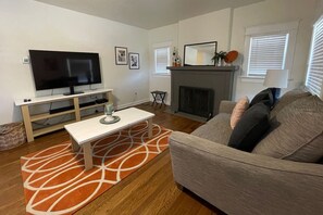 A living room with a TV, sofa, and fireplace. - Tangerine Oasis - Homey & newly renovated 2 BR! (Amarillo)