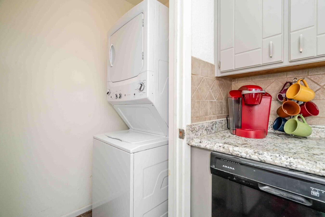 A compact kitchen with a white washing machine, a red coffee maker, and a dishwasher.
