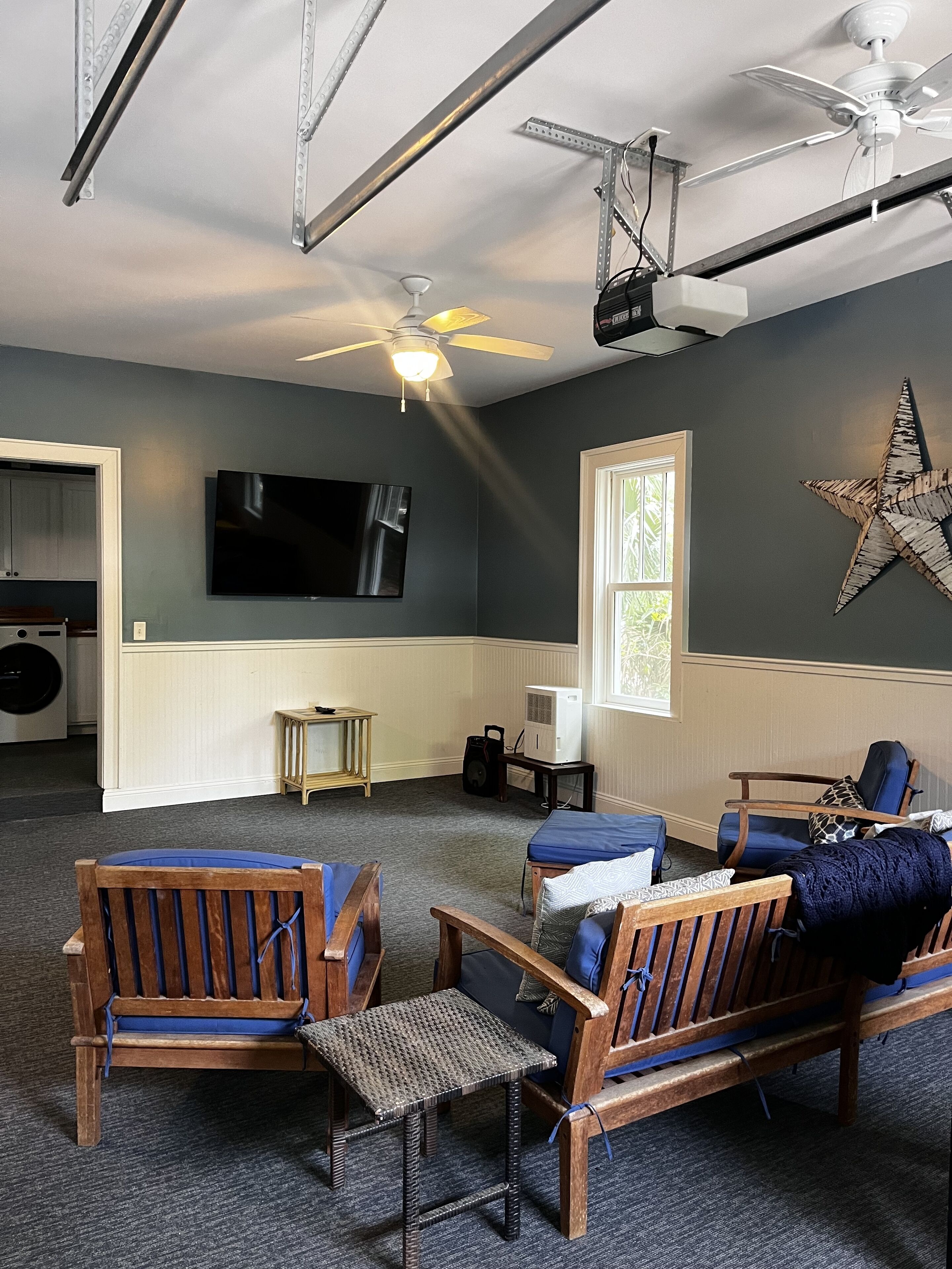 A living room with a ceiling fan, a mounted TV, and a star decoration on the wall.