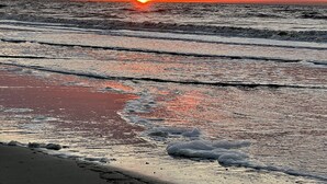 Ein Strand mit Wellen und einem Sonnenuntergang.