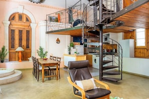 Eine Mehrstöckige Wohnung mit Essbereich, Lounge-Sessel, Treppe und Küche.