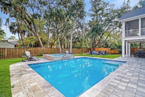 Relax by the pool surrounded by lush trees and a patio area.