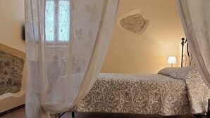 Ein Schlafzimmer mit Baldachinbett, Steinwand und einer Lampe.