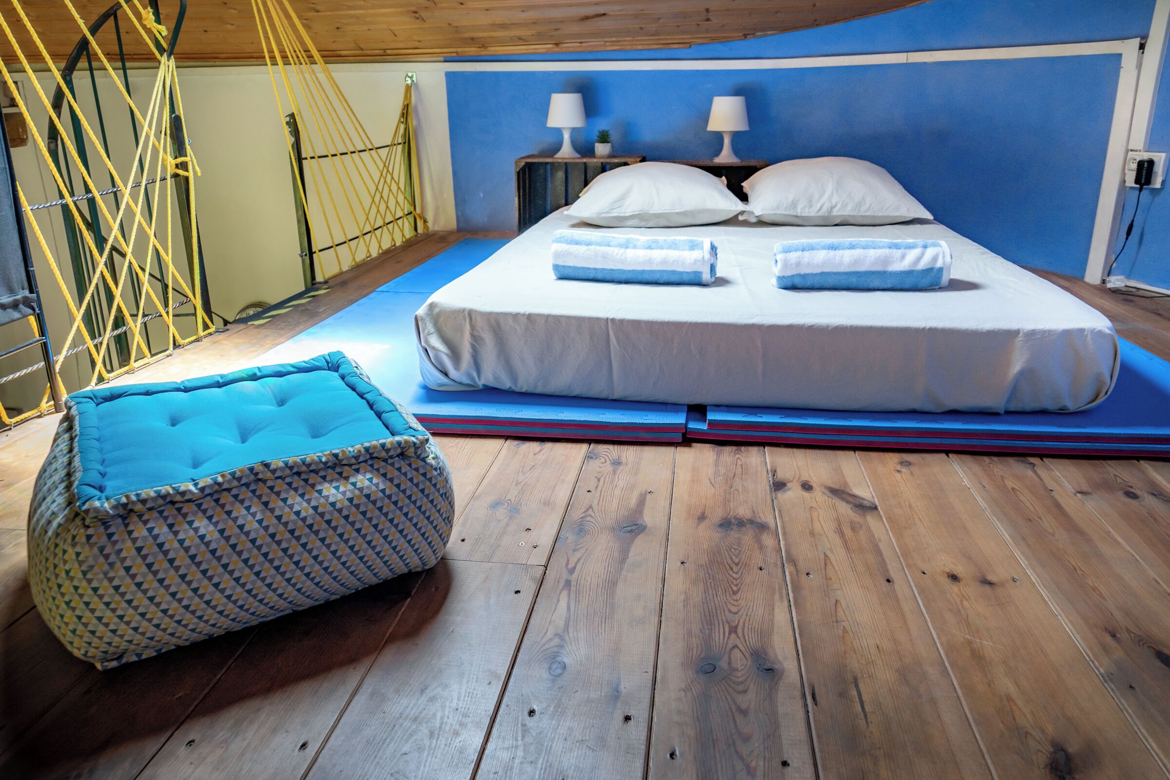 Un dormitorio con cama, dos lámparas de noche, una planta pequeña y un sillón de felpa estampado.
