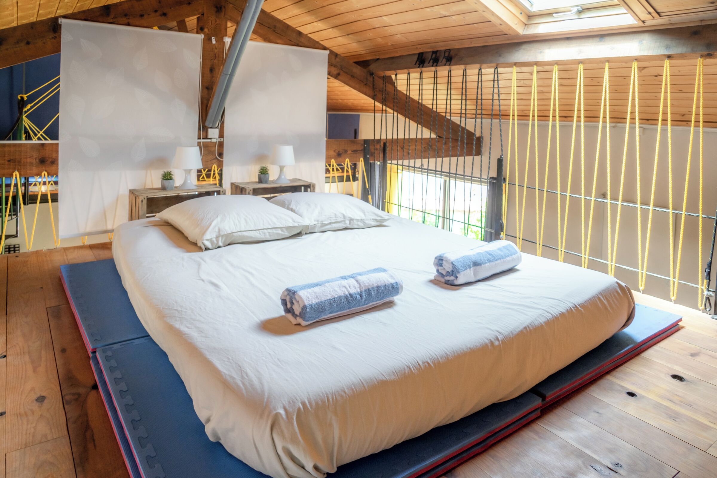 Une chambre dotée d’un grand lit, d’un plancher en bois, d’une lucarne et offrant une vue sur l’extérieur.