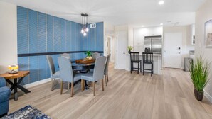 Un'area pranzo moderna con una parete decorata con un motivo blu, un tavolo da pranzo in legno e sedie rivestite in grigio.