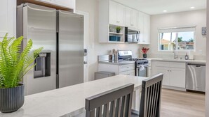 Una cucina moderna con elettrodomestici in acciaio inossidabile, mobili bianchi e un angolo bar.