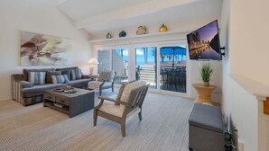 Un salon spacieux comprenant un canapé, un fauteuil et une table basse. Une grande fenêtre offre une vue sur la ville.