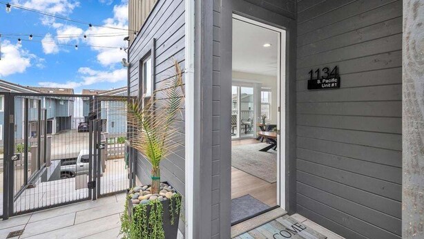A modern building entrance with a welcome mat, a number sign, and a view of the interior. - Oceanview Escape | Tower 9 Condo Steps from the Beach (Oceanside)