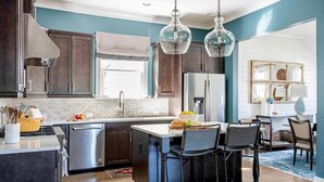 Une cuisine moderne avec des meubles de couleur sombre, des appareils en acier inoxydable et un îlot central doté de tabourets de bar.