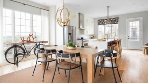 A modern kitchen with a dining area, large windows, and a bicycle. - Sky's the Limit (Atlanta)