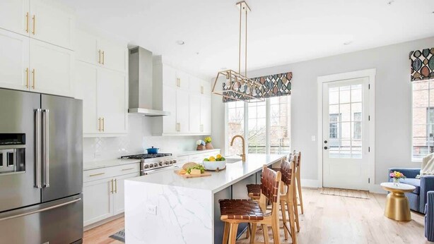 A modern kitchen with white cabinetry, stainless steel appliances, and a marble island. - Sky's the Limit (Atlanta)
