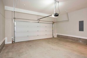 A garage with a closed garage door, a ceiling-mounted light fixture, and a door on the right side.