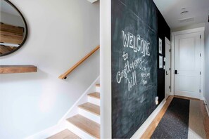 A staircase with a wooden handrail and a wall with a chalkboard sign that reads "WELCOME to Castaway Hill." - Bird's Eye View (Atlanta)
