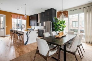 A modern kitchen with dark cabinets, a central island, and a dining area with a large table and chairs. - Bird's Eye View (Atlanta)