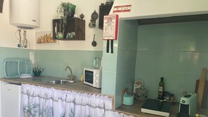 A kitchen with a microwave, sink, and a sign indicating a water heater.