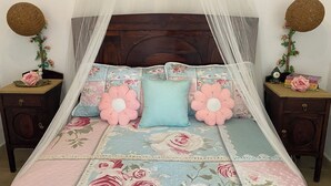 Un lit avec une couvre-lit à motifs floraux, un baldaquin et des coussins décoratifs.