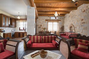 Una sala acogedora con un conjunto de sofás, muebles de madera y una pared de piedra.