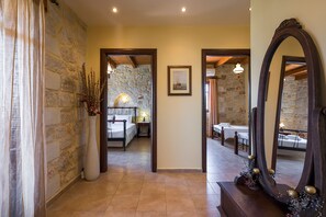Un pasillo de hotel con paredes de piedra, una cama, una zona de comedor y un espejo grande.