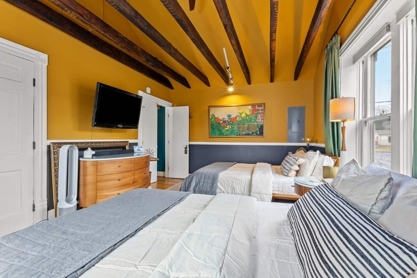 Una habitación de hotel con una cama, un aparador, una televisión y un cuadro en la pared.