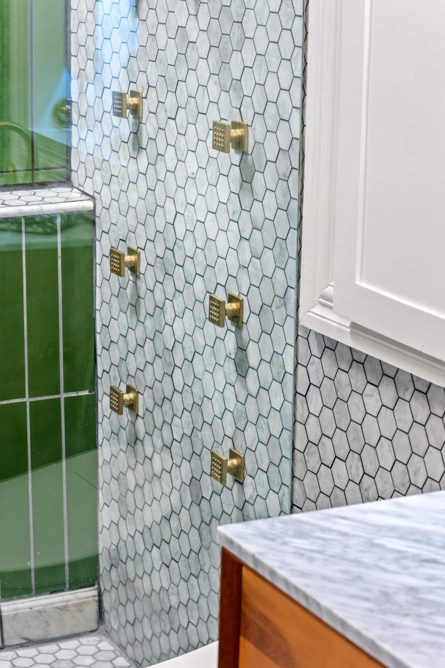 A bathroom with hexagonal patterned tiles, brass fixtures, and a marble countertop.