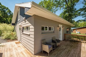 Ein zweistöckiges Haus mit einer Terrasse, einer kleinen Veranda mit Korbmöbeln und einer sichtbaren Garagentür.