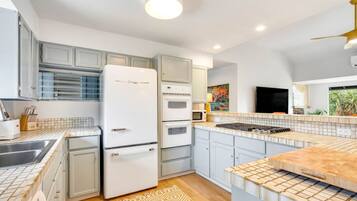 A modern kitchen with white appliances, light blue cabinets, and a patterned rug.