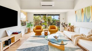 A modern living room with a sofa, two armchairs, a coffee table, and a TV. - Cool, Lo-Fi Styled Surf Shack - Ka Hale Nalu (Princeville)