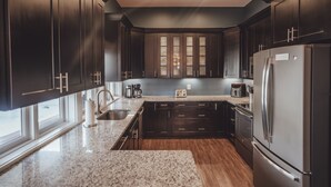 Une cuisine moderne avec des meubles en bois foncé, des appareils électroménagers en acier inoxydable et un plan de travail en granit.