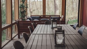 Une table en bois, avec des bancs et des chaises, une plante en pot et une lanterne posée sur la table.