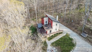 Une maison moderne avec une façade rouge et blanche, un patio couvert et une allée gravillonnée.