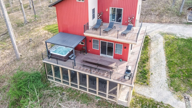 Une maison à deux étages dotée d’un jacuzzi au rez-de-chaussée, d’un balcon avec des sièges et d’une grande fenêtre à l’étage.