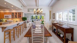 A spacious kitchen with a central island, wooden chairs, and a dining table. - Fabulous Island Getaway! Easy access to Florida Bay, Private Beach,  Elevator (Islamorada)
