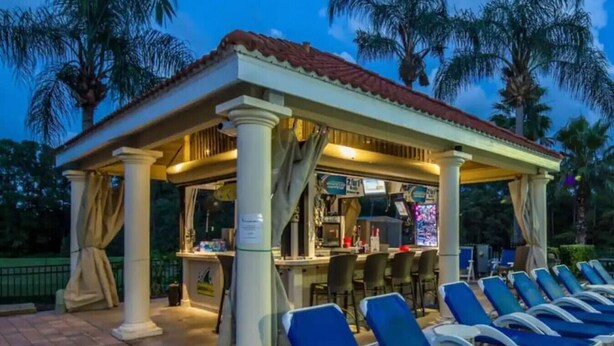 Un área de bar al aire libre con sillones y una barra.