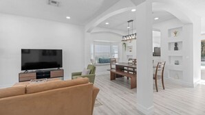 Un salón amplio con televisión de pantalla plana, un sofá y un comedor con mesa y sillas.