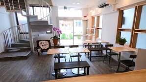 Un restaurante con piso de madera, mesas, sillas, una escalera y una planta en maceta.
