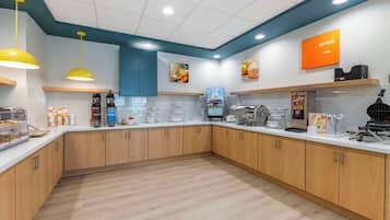 Un espacio moderno de cocina con armarios de madera, encimera blanca y varios electrodomésticos.