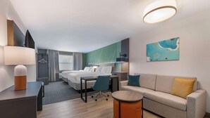 A modern hotel room with a bed, a sofa, a desk, and a round table. - Comfort Suites St. Augustine Historic District Area (St. Augustine)