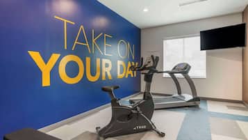 Une salle de sport dotée d’un mur d’inspiration, d’appareils d’exercice et d’un téléviseur.
