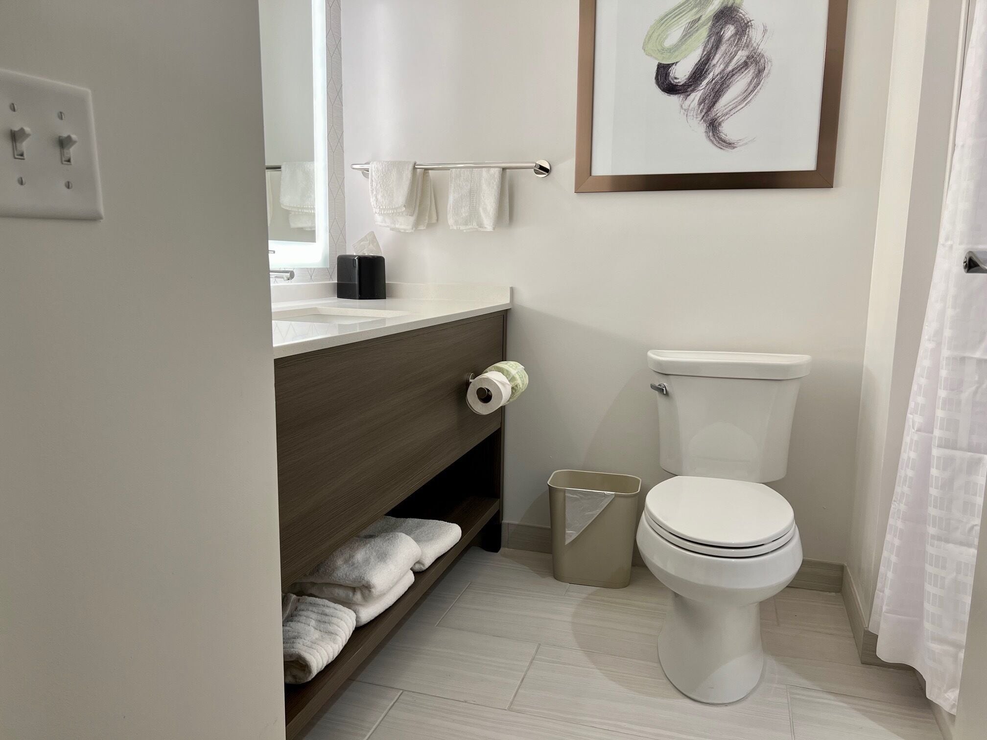 Une salle de bain moderne équipée d’un WC, d’un lavabo, d’un porte-serviettes et d’une poubelle.