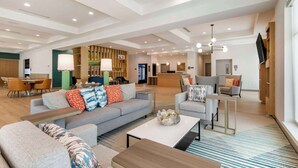 A spacious hotel lobby with a modern design, featuring a reception desk, seating area with sofas and chairs, and a large television on the wall. - Comfort Suites St. Augustine Historic District Area (St. Augustine)